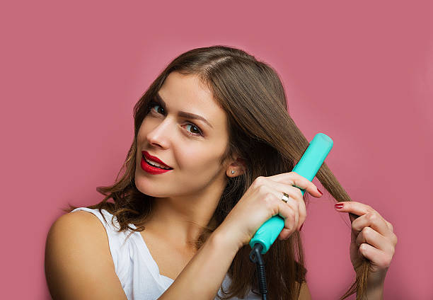 Beautiful woman with a wavy hair holding a hair iron stock photo