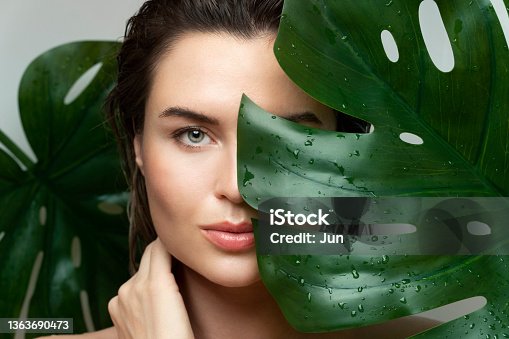 istock Beautiful woman with a wet tropical leaf 1363690473