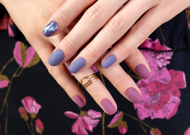 Beautiful womans hand with purple matte manicure on fabric stock photo