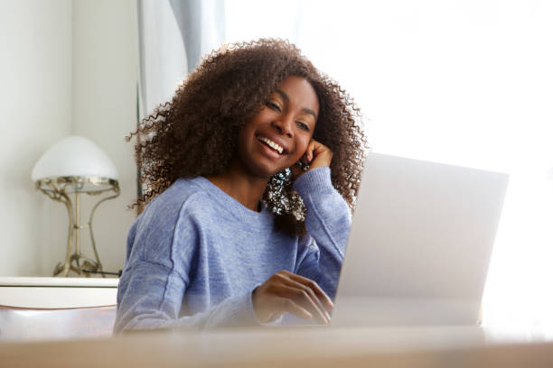 beautiful young african american woman looking at laptop and smiling stock photo
