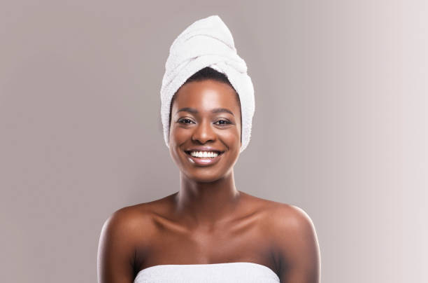 Beautiful young african woman wrapped in white bath towel Beautiful young african woman wrapped in white bath towel preparing for sauna, grey studio background towel stock pictures, royalty-free photos & images