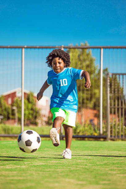 Beautiful young black boy training on the football pitch stock photo