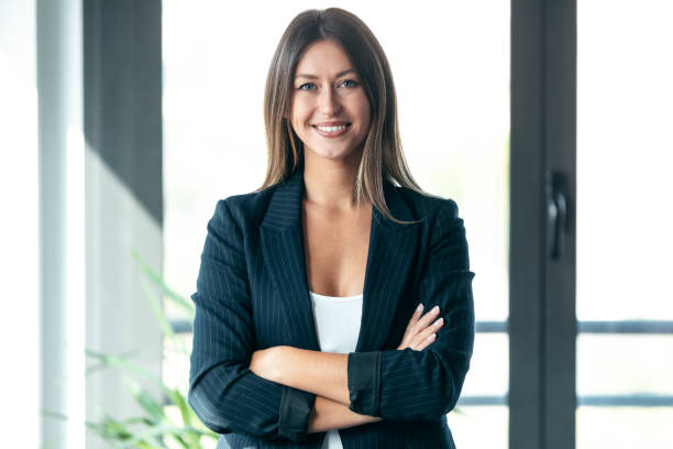 Beautiful young business woman standing while smiling looking at camera in the office. stock photo