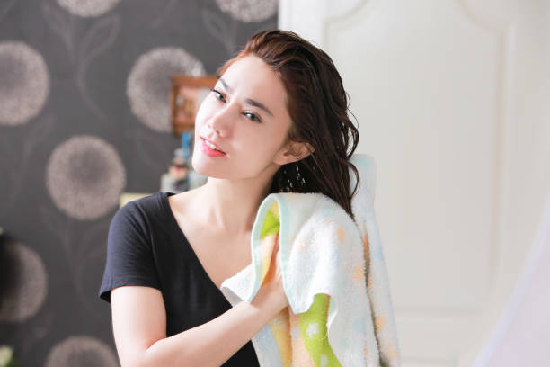 Beautiful Young Female After Bath Applying Hair Oil. stock photo