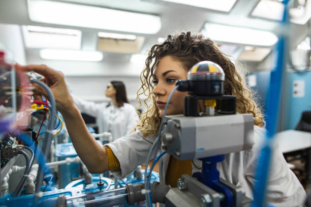 Beautiful young female engineer working in mechanical laboratory stock photo