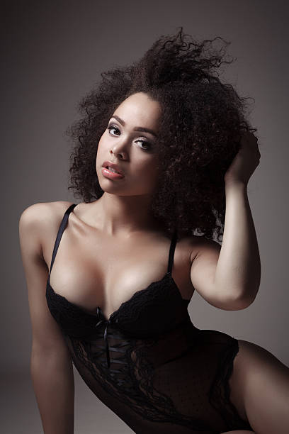 Beautiful young female with dark curly hair posing in lingerie stock photo