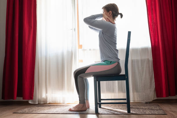 Beautiful young girl doing exercises at home using chair. Beautiful young girl doing exercises at home using chair. Variations for opening the shoulders. Side view chair stock pictures, royalty-free photos & images