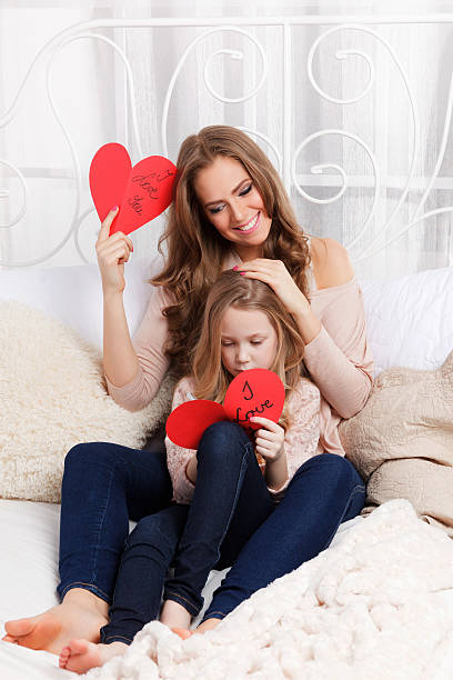 Beautiful young mother and daughter in the bed stock photo