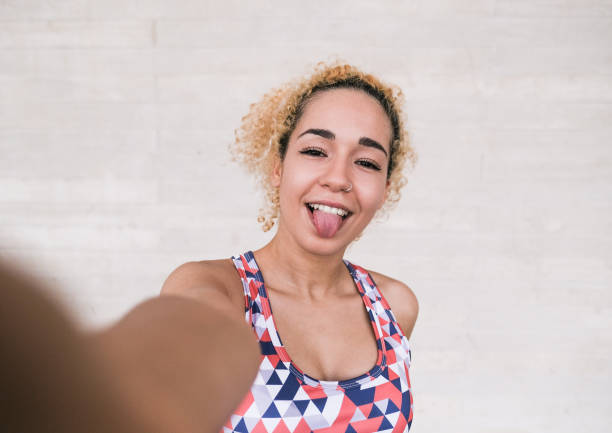 Beautiful young multiracial woman taking a selfie with tongue out Beautiful young multiracial woman taking a selfie with tongue out healthy tongue stock pictures, royalty-free photos & images