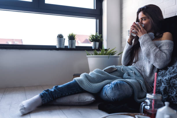 Beautiful young woman at home drinking coffee by the window Beautiful young woman at home drinking coffee by the window beautiful swedish women stock pictures, royalty-free photos & images