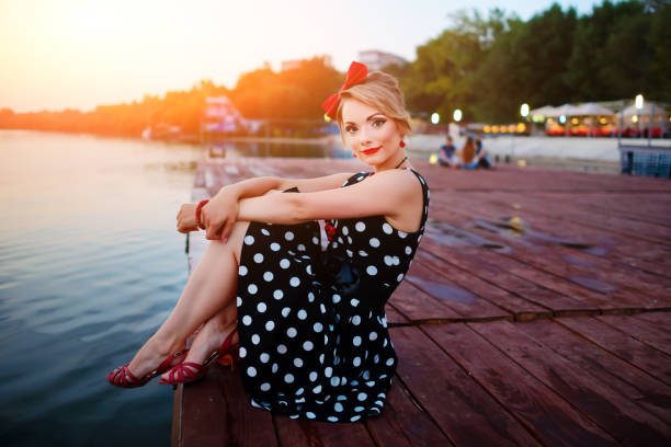 A beautiful young woman dressed sitting on the pier stock photo