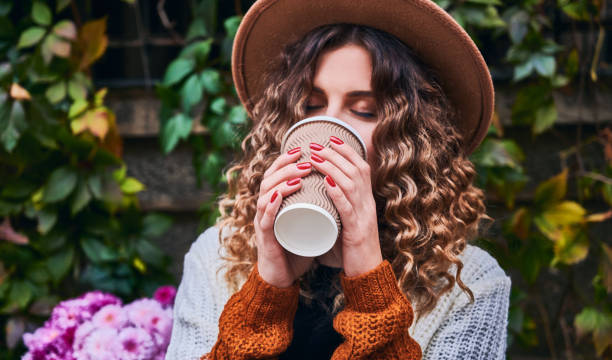 Beautiful young woman drinking coffee on the street. stock photo