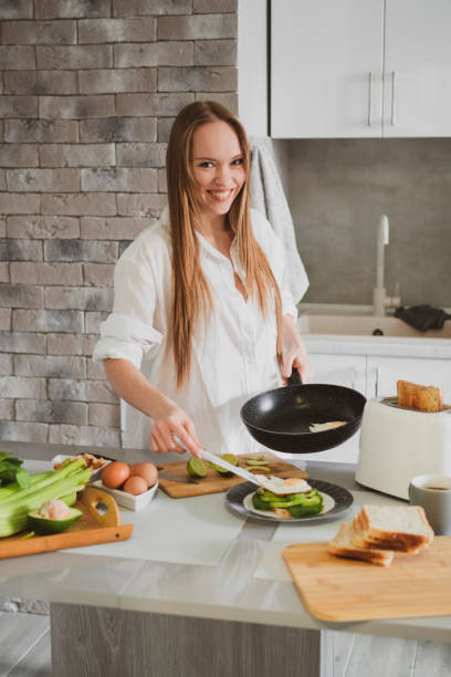 Beautiful young woman in the kitchen at home prepares healthy food stock photo