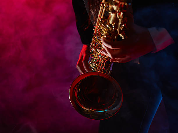 Beautiful young woman plays saxophone stock photo