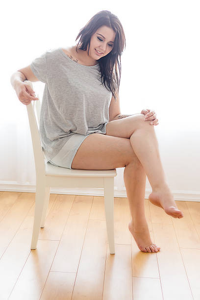 bellissima giovane donna seduta su una sedia - accavallare le gambe foto e immagini stock