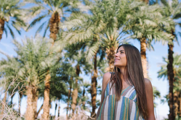 Beautiful young woman surrounded by palm trees and date palms Holidays woman smiling on tropical beach summer vacation with palm trees and date palms vlad model photos stock pictures, royalty-free photos & images