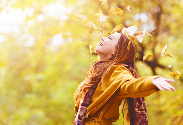 bellissima giovane donna buttare foglie in un parco - autunno energia foto e immagini stock