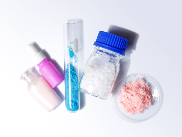 Beauty care cream, serum, Copper(II) sulfate in test tube and Microcrystalline wax in glass container place next to himalayan pink salt in chemical watch glass. Top View stock photo