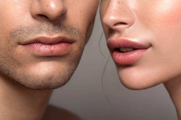 Beauty couple Closeup studio shot of a beautiful young woman and man posing against a grey background human lips stock pictures, royalty-free photos & images