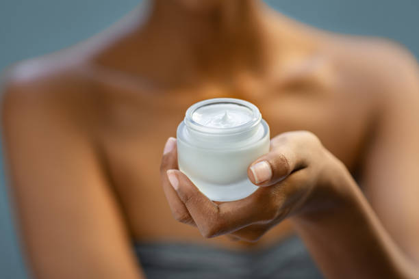 Beauty moisturizer for face treatment closeup Closeup of african woman holding moisturizer cream jar. Detail of black hands holding face lotion. Woman showing white moisturiser for healthy skin. applying face cream stock pictures, royalty-free photos & images