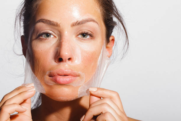 Beauty portrait of a young woman applying-removing face peeling mask stock photo