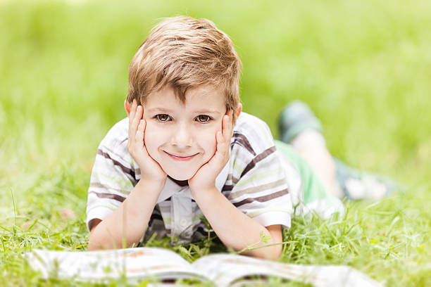 Beauty smiling child boy reading book outdoor stock photo