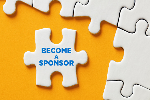 Become a sponsor message on a puzzle piece apart form the assembled pieces. Financial sponsorship support or charity donation concept.