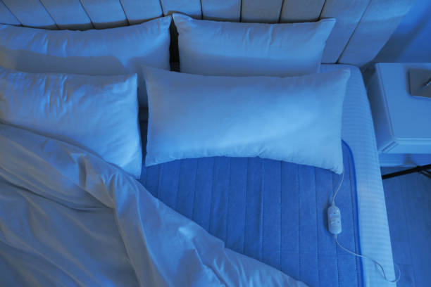 cama con almohadilla térmica eléctrica en el interior por la noche - colchones nuevos fotografías e imágenes de stock