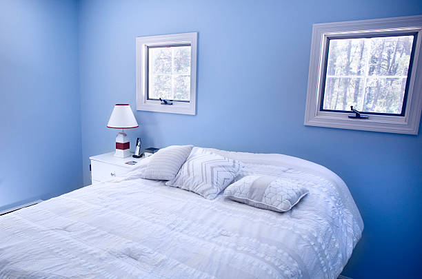 Bedroom with blue walls and windows. stock photo