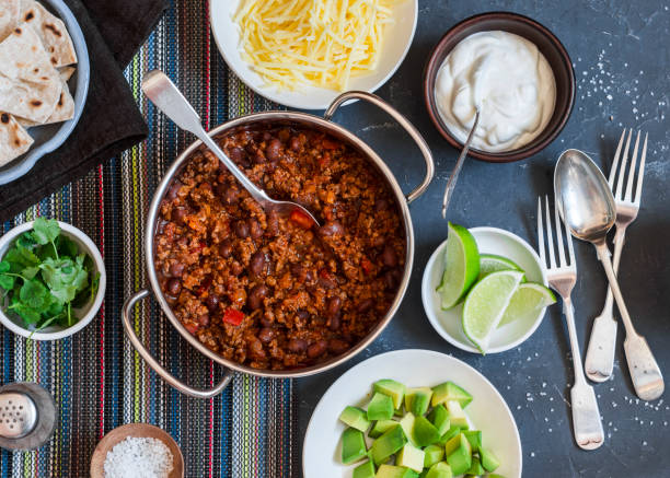 Beef and black bean chili bar on dark background, top view. Flat lay stock photo