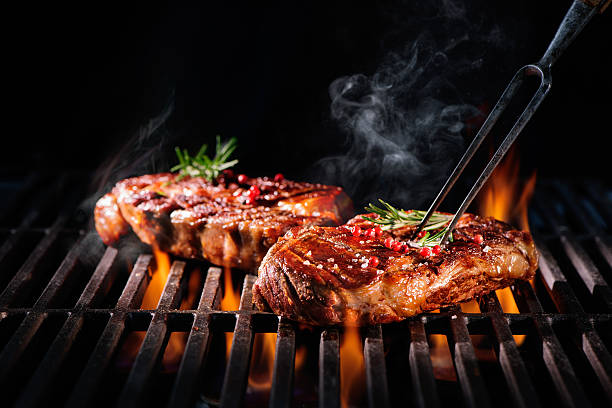 Beef steaks on the grill Beef steaks on the grill with flames cut of meat stock pictures, royalty-free photos & images