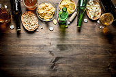 Beer and an assortment of different types of snacks. On wooden background