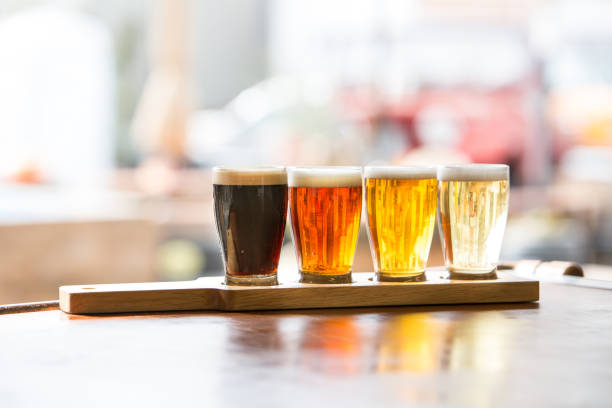 Beer Flight tasting in Glasses on Wood Plank Microbrewery tasting flight in row of smaller glasses set in wood plank with sunlight flooding in tasting stock pictures, royalty-free photos & images