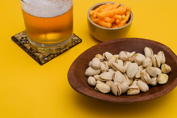 Beer with salty appetizer on yellow background stock photo