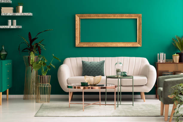 a beige sofa in a teal backgound with gold accessories
