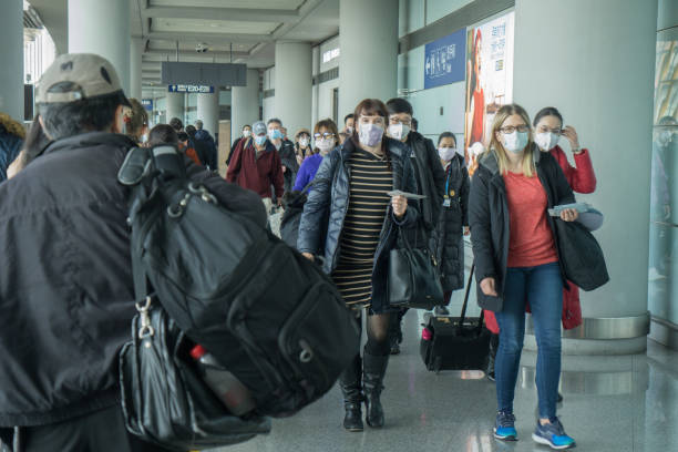 Beijing, Cina, 31 Januari 2010: Bandara Internasional Ibu Kota Beijing selama wabah virus Corona. Virus ini telah menyebar dengan cepat dan menjadi darurat kesehatan global. Di bandara semua orang memakai masker. Di antara penumpang adalah beberapa orang asing / barat.