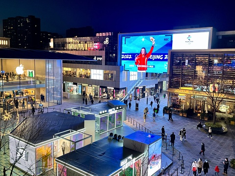 March 20, 2022: Beijing; Taikuli Shopping Center in Beijing featuring large video screen with Olympic Gold Medalist Eileen Gu, as shoppers throng the plaza.