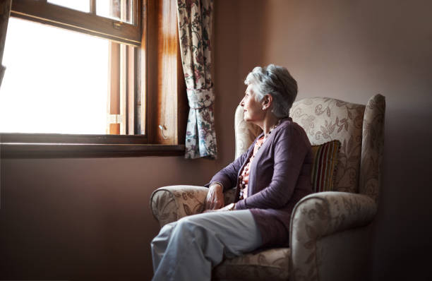Being alone is something we all have to experience Shot of a senior woman sitting alone in her living room memory loss stock pictures, royalty-free photos & images