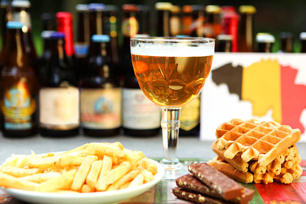 Belgian Food and Drinks: Beer, Waffles, Chocloate, Fries This is an image of all the food and drinks that Belgium is famous for: Belgian beer, Belgian waffles, Belgian chocolate, and traditional fries with mayonnaise. A variety of Belgian beer bottles are out of focus in the background, as well as a drawing of a Belgian map in Belgian flag colors. belgian culture stock pictures, royalty-free photos & images