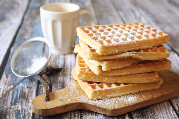 Belgian waffles, powdered sugar dressing and coffee cup for sweet breakfast stock photo