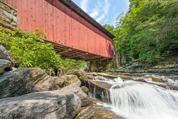 Below Packsaddle Covered Bridge Built in 1887, the historic Packsaddle Covered Bridge crosses over a waterfall on Brush Creek in rural Somerset County, Pennsylvania. covered bridge stock pictures, royalty-free photos & images