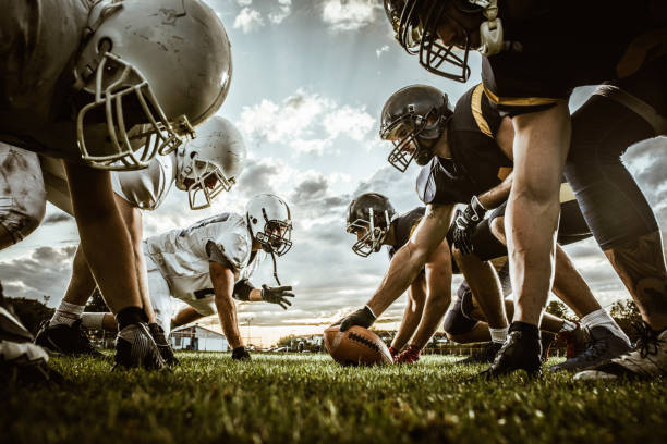 Below view of American football players on a beginning of the match. Low angle view of American football players confronting before the beginning of a match. football stock pictures, royalty-free photos & images