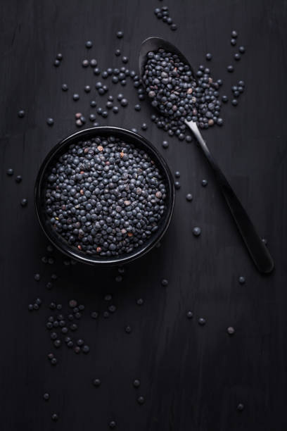Beluga lentils on black background. Black lentils in bowl with spoon. Beluga lentils on black background. Black lentils in bowl with spoon. beluga whale stock pictures, royalty-free photos & images