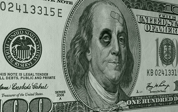 Ben Franklin with Black Eye and Band Aid on C-Note Ben Franklin with sports a shiner (black eye) and a band-aid on the face of a US One Hundred Dollar Bill (C-Note) as an illustration of the weak dollar. black eye stock pictures, royalty-free photos & images