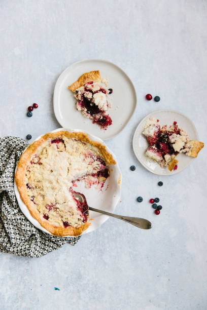 A berry pie with two slices on plates stock photo