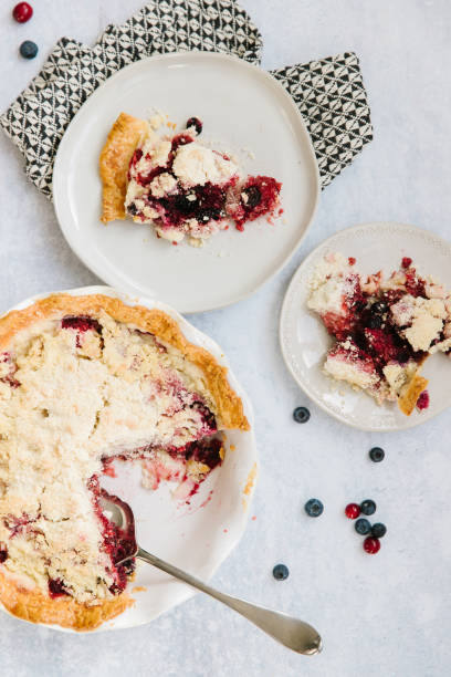 A berry pie with two slices on plates stock photo