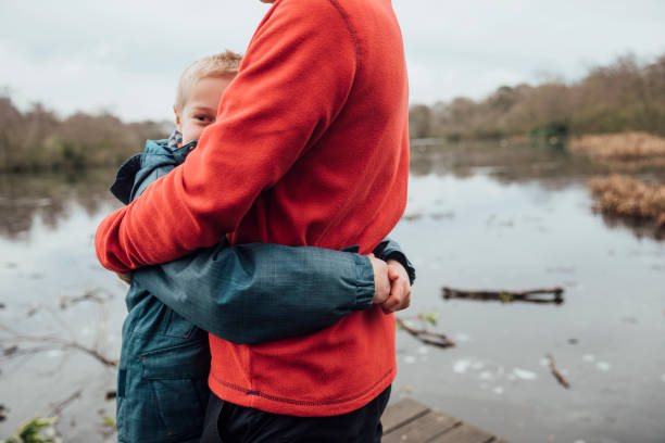 Best Dad Ever Father and son on a day out to Bolam Lake in Northumberland. It is cold weather during winter and they are standing beside the lake hugging each other. fathers day stock pictures, royalty-free photos & images