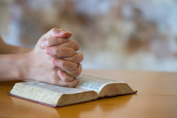 bible, hands of women praying stock photo