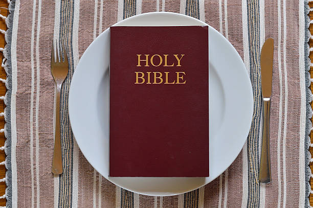 Bible on a dinner plate with silverware in lent. stock photo
