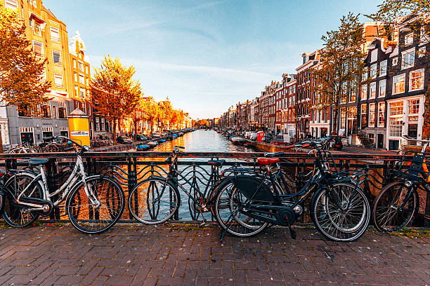Pemandangan kota Amsterdam dengan banyak taman sepeda di kanal air dan jembatan khas di hari yang cerah